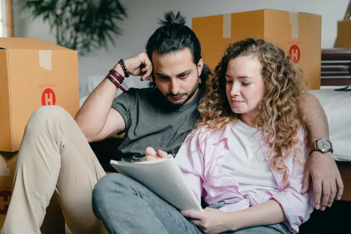 Couple checking a moving list beside boxes