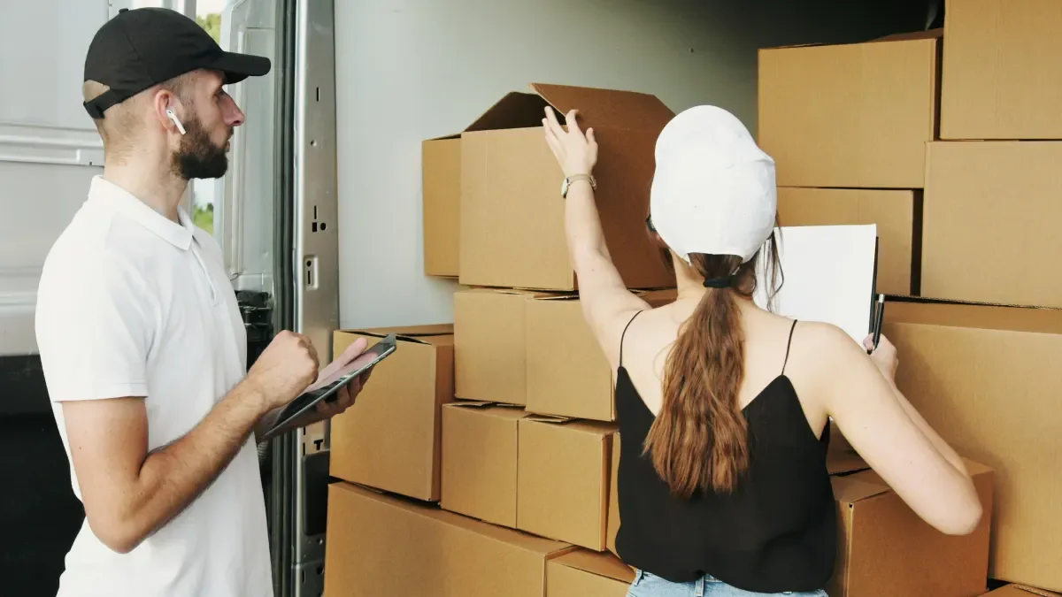 Man holding a moving box beside a stack of boxes