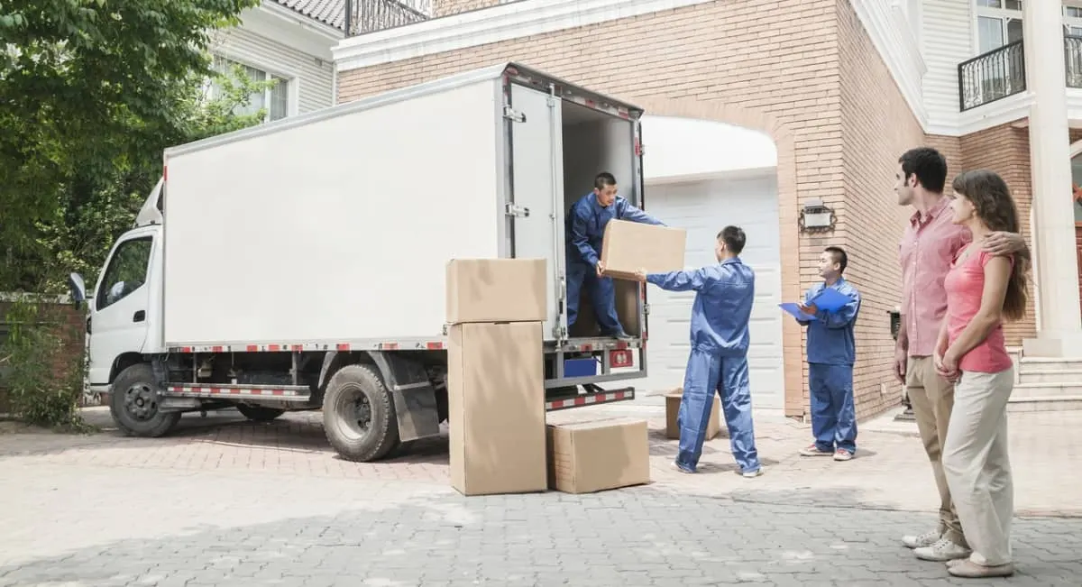 Movers loading boxes beside a white van