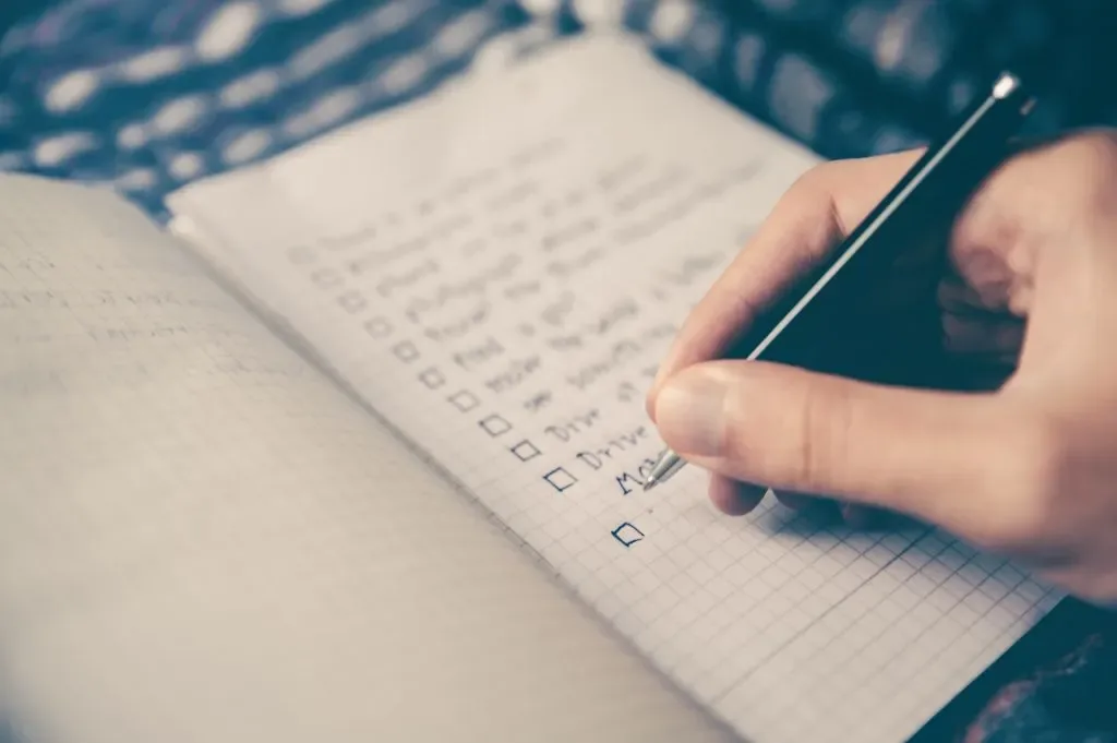 Person writing a moving checklist in a notebook