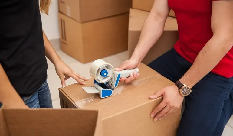 Packing a cardboard box with household items