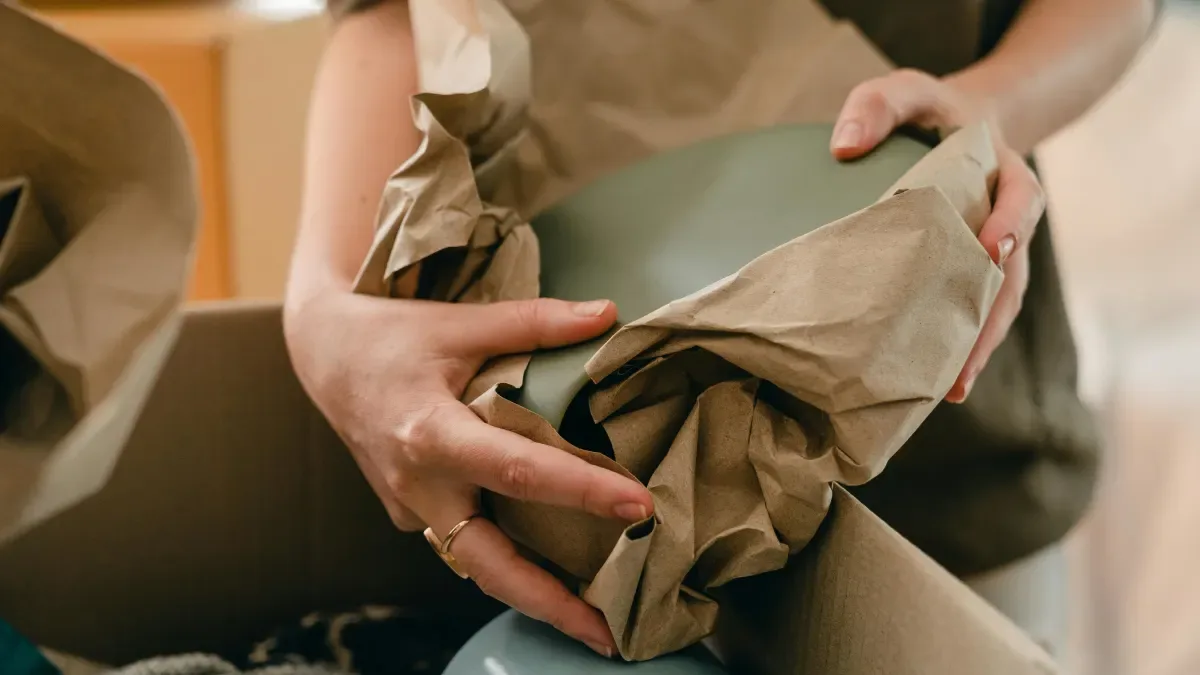 Hands wrapping an item before packing