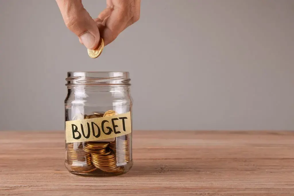 Coins being added to a jar labelled budget