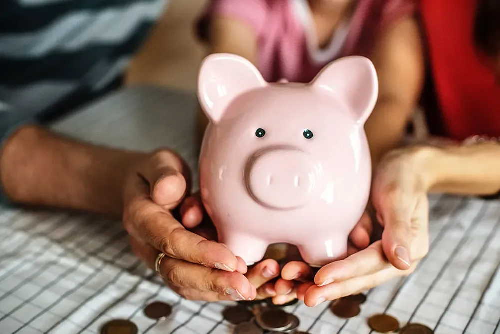 Coins being saved in a pink piggy bank